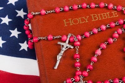 Red rosary with cross with Catholic bible on American flag. Studio shot with Canon 5D Mark II and Canon 100mm f2.8 Macro lens.